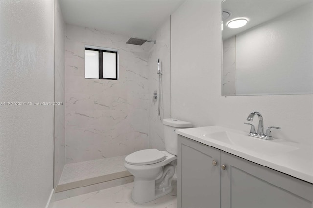 bathroom featuring toilet, vanity, and tiled shower