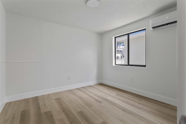 spare room featuring light wood-type flooring and an AC wall unit