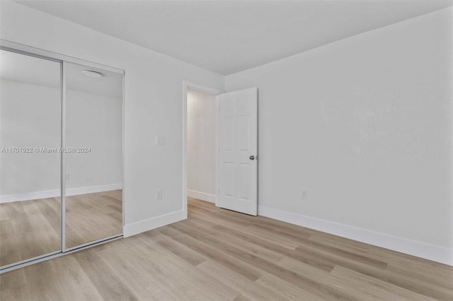 unfurnished bedroom with a closet and light hardwood / wood-style floors