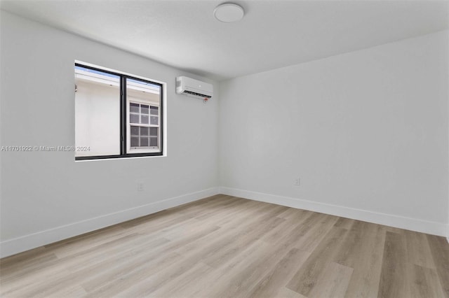 empty room featuring light hardwood / wood-style floors and an AC wall unit