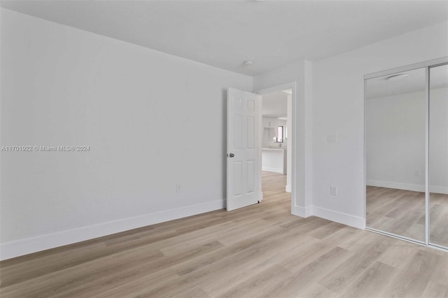 unfurnished bedroom with light hardwood / wood-style floors and a closet