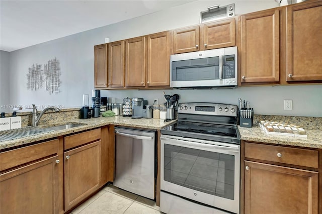 kitchen featuring light stone countertops, light tile patterned floors, stainless steel appliances, and sink