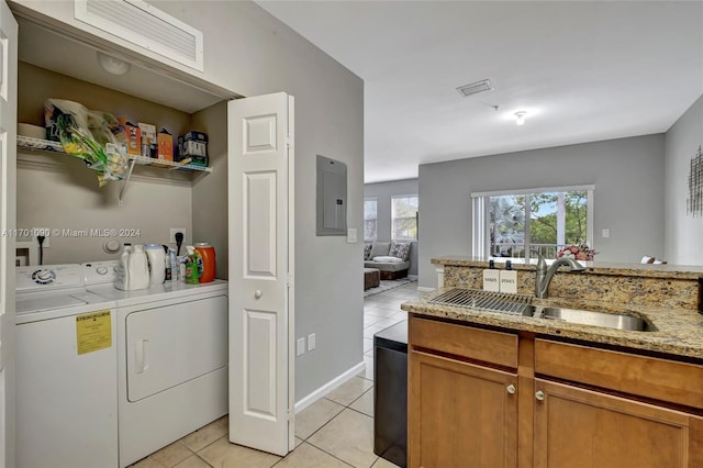 washroom with light tile patterned floors, sink, electric panel, and washing machine and clothes dryer