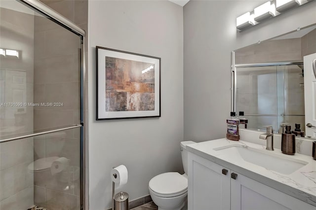 bathroom with vanity, a shower with shower door, and toilet