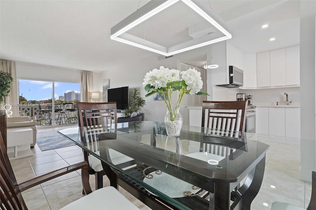 dining area with light tile patterned floors, a textured ceiling, and sink