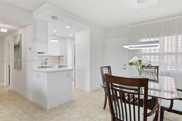 kitchen featuring pendant lighting, light tile patterned floors, white cabinetry, and sink