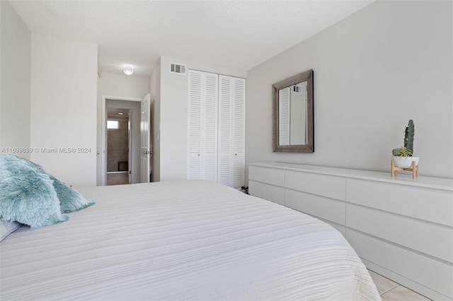 bedroom with a closet, light tile patterned floors, and a textured ceiling