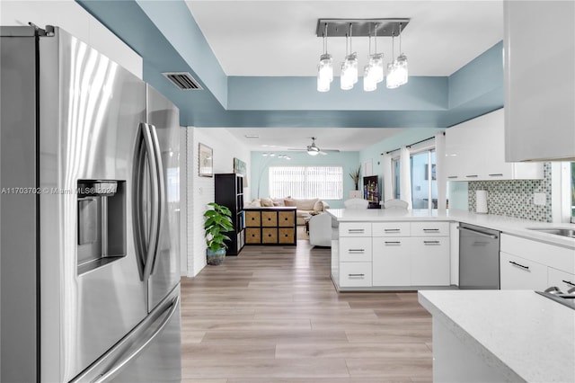 kitchen featuring white cabinetry, ceiling fan, stainless steel appliances, decorative light fixtures, and light wood-type flooring