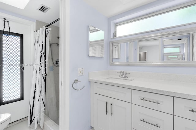 bathroom with vanity, toilet, curtained shower, and a healthy amount of sunlight