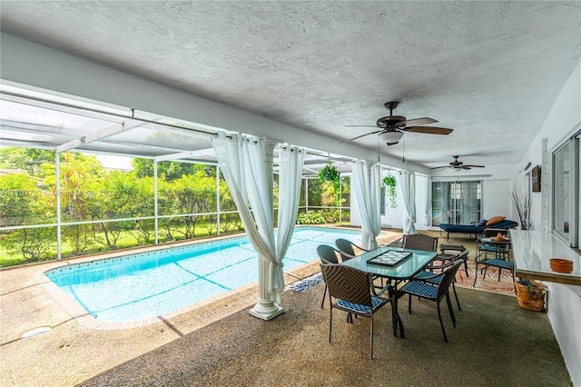 view of pool with a patio, glass enclosure, and ceiling fan