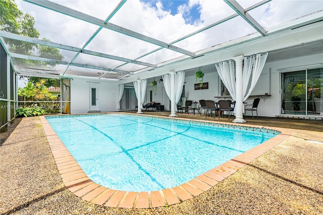 view of pool featuring glass enclosure and a patio