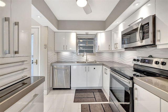 kitchen with white cabinets, sink, decorative backsplash, light tile patterned floors, and stainless steel appliances