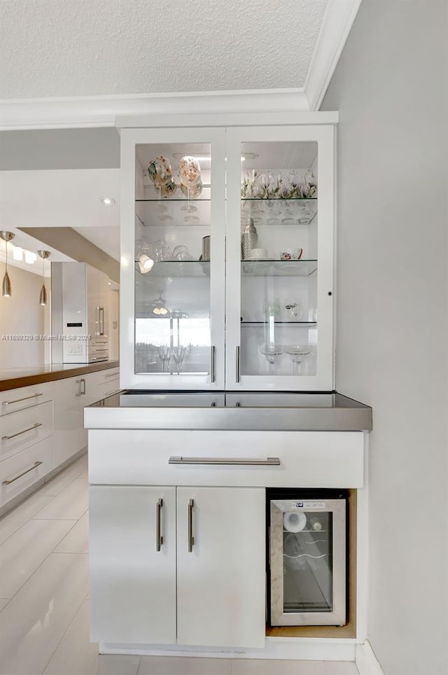 bar with white cabinetry, a textured ceiling, beverage cooler, and ornamental molding