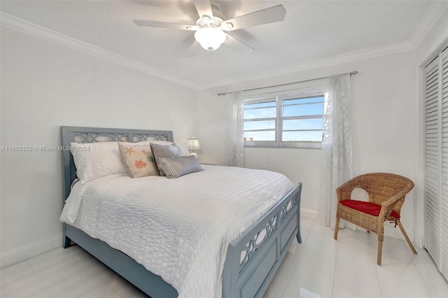 bedroom featuring ceiling fan, a textured ceiling, a closet, light tile patterned flooring, and ornamental molding