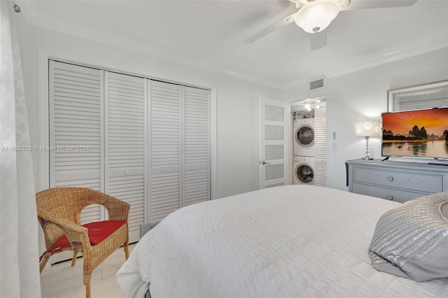 bedroom featuring ceiling fan, crown molding, and stacked washer and clothes dryer