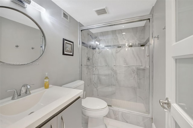 bathroom featuring tile patterned floors, vanity, a shower with shower door, and toilet