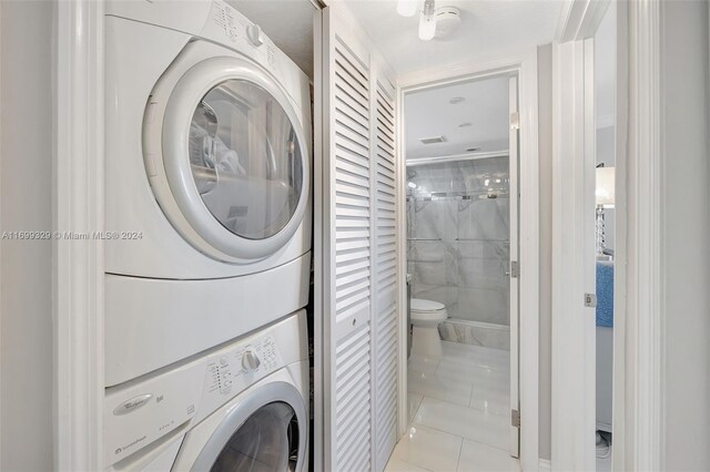 washroom with stacked washer / drying machine and light tile patterned floors