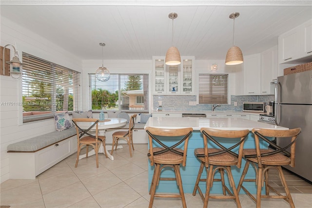 kitchen featuring appliances with stainless steel finishes, backsplash, white cabinetry, and pendant lighting