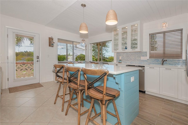 kitchen with a kitchen breakfast bar, a kitchen island, dishwasher, white cabinetry, and hanging light fixtures