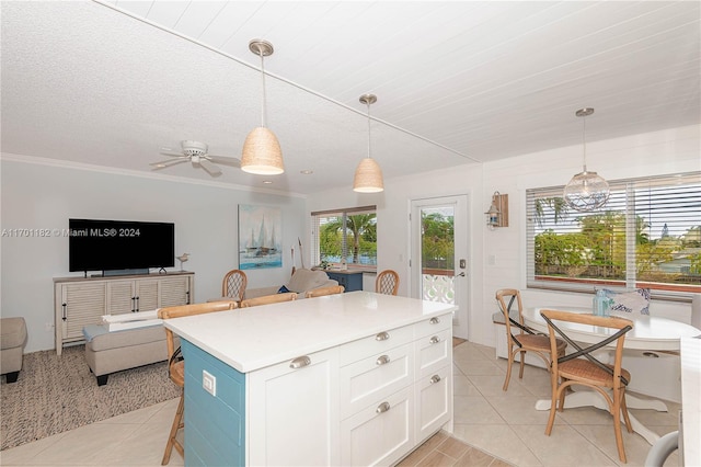 kitchen with ceiling fan, light tile patterned floors, a kitchen island, pendant lighting, and white cabinets