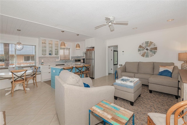 living room featuring ceiling fan, sink, light tile patterned flooring, and a textured ceiling