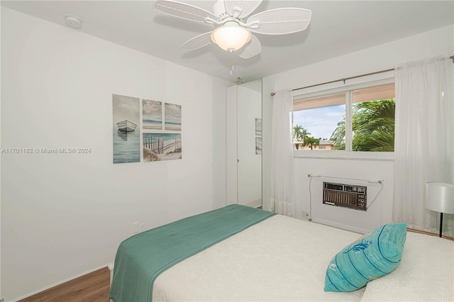 bedroom featuring a wall mounted AC, hardwood / wood-style flooring, ceiling fan, and a fireplace