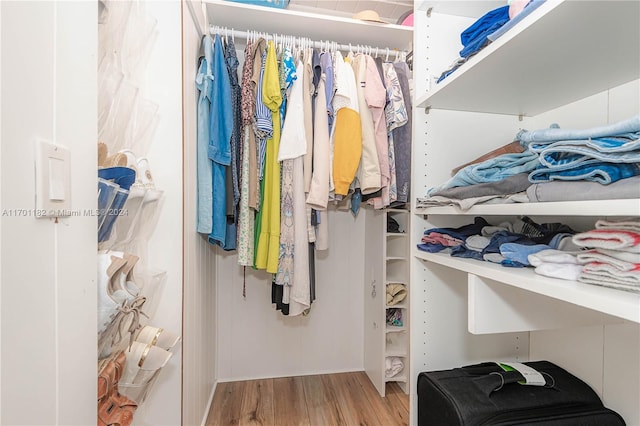 walk in closet with light hardwood / wood-style floors