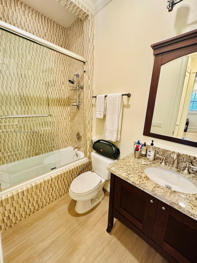 full bathroom with enclosed tub / shower combo, hardwood / wood-style floors, toilet, vanity, and ornamental molding