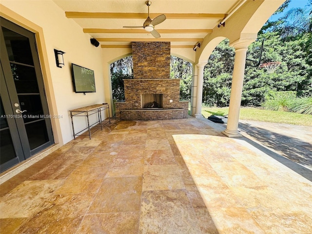 view of patio with an outdoor stone fireplace, french doors, and ceiling fan