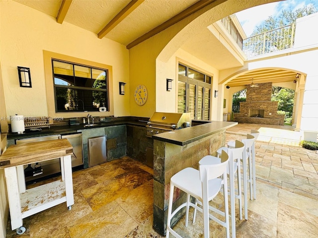 view of patio with an outdoor stone fireplace, a bar, area for grilling, and grilling area