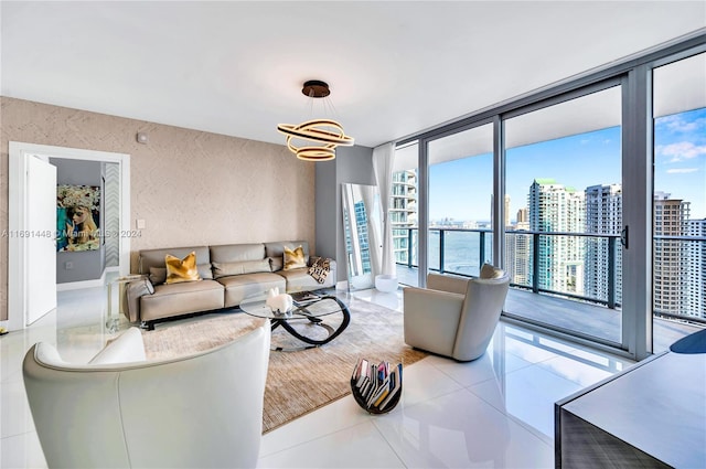 living room featuring expansive windows, a water view, light tile patterned floors, and an inviting chandelier