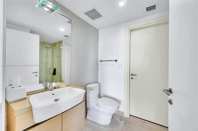 bathroom with tile patterned floors, vanity, toilet, and a shower with door