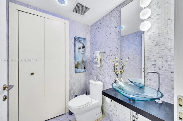 bathroom featuring decorative backsplash, toilet, and sink