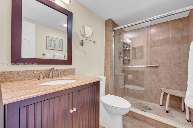 bathroom featuring tile patterned flooring, vanity, toilet, and a shower with shower door