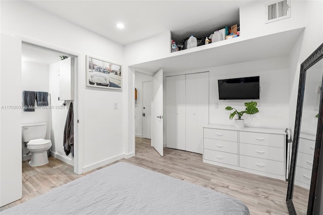 bedroom featuring a closet, connected bathroom, and light hardwood / wood-style flooring