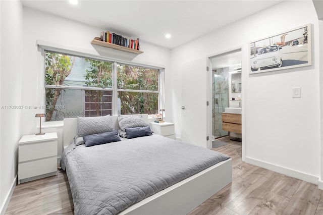 bedroom featuring connected bathroom and light wood-type flooring