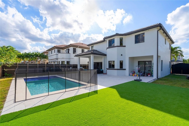 back of property with a lawn, a patio, and a fenced in pool