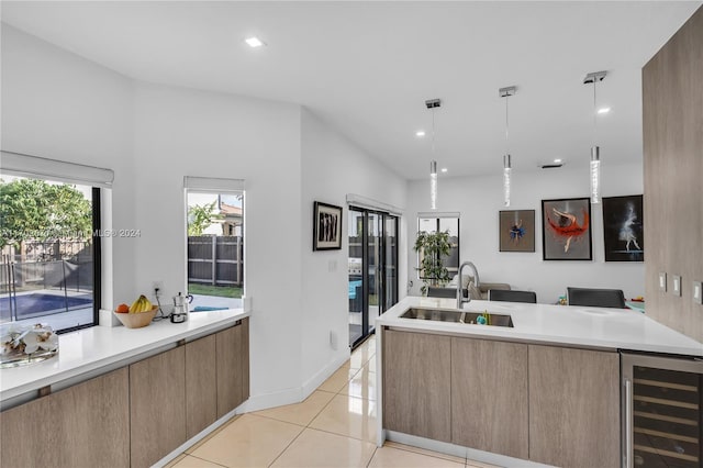 kitchen with sink, wine cooler, hanging light fixtures, and light tile patterned flooring