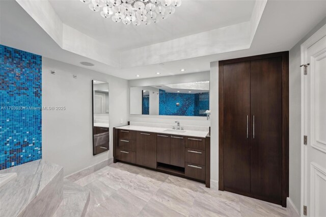 bathroom featuring a chandelier, vanity, and a tray ceiling