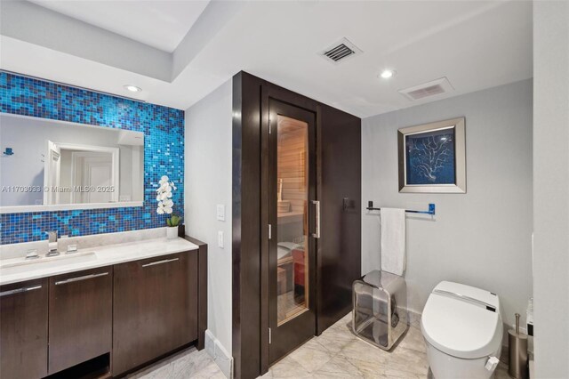 bathroom with decorative backsplash, vanity, and toilet