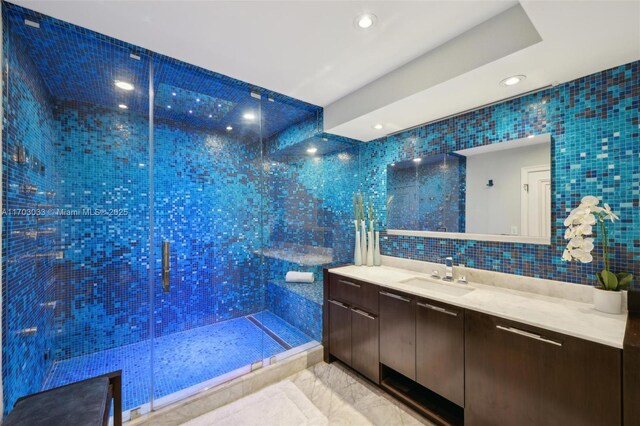 bathroom featuring tile patterned flooring, a tile shower, vanity, and tile walls