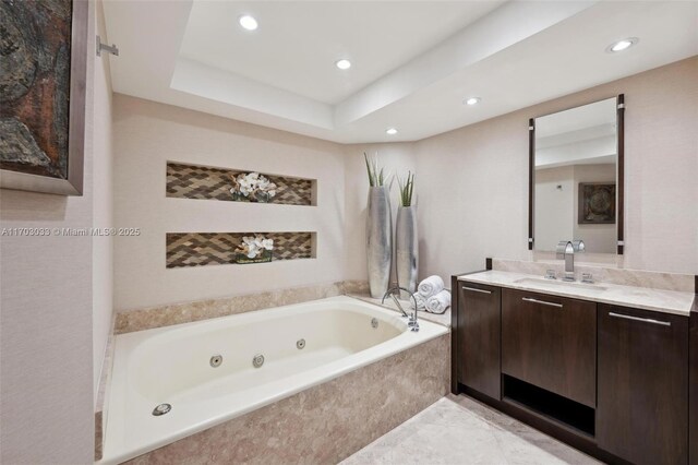 bathroom featuring vanity, a raised ceiling, and tiled tub