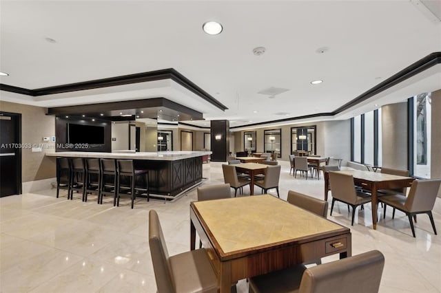 dining room with light tile patterned floors, a tray ceiling, and ornamental molding