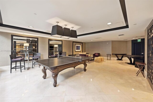 recreation room with light tile patterned floors and a raised ceiling