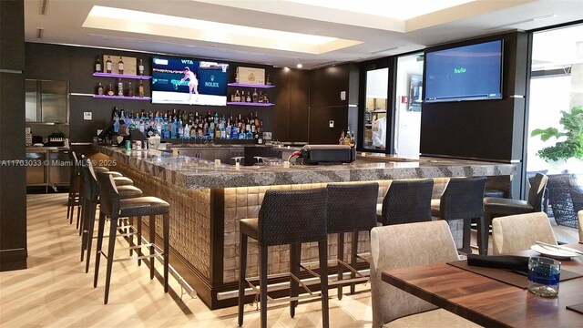 bar with floor to ceiling windows and light hardwood / wood-style flooring