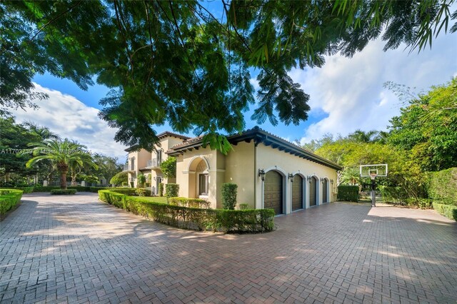 5935 Moss Ranch Rd, Pinecrest, FL 33156 - view of side of property featuring stucco siding, decorative driveway, and a garage