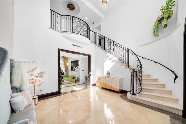 foyer with a towering ceiling and ornamental molding