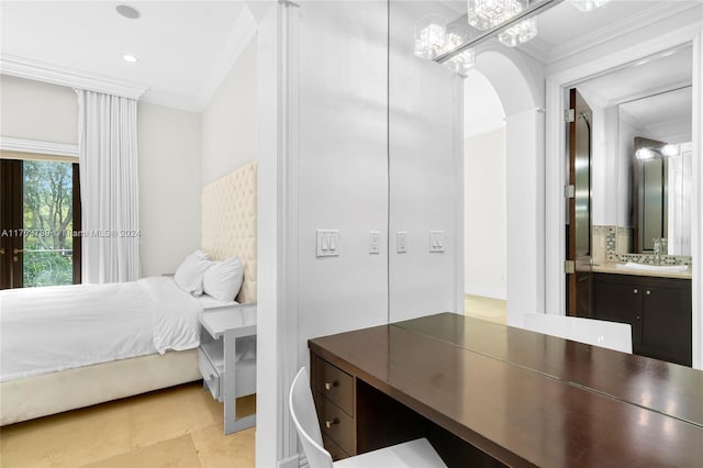 bedroom featuring ensuite bath, ornamental molding, and sink