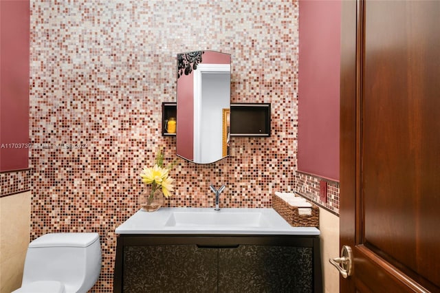 bathroom featuring vanity, toilet, and decorative backsplash