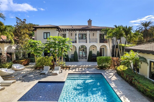 5935 Moss Ranch Rd, Pinecrest, FL 33156 - rear view of house featuring a balcony, a chimney, a patio, stucco siding, and an outdoor pool